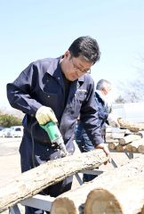 原木に菌を埋め込むための穴を開ける作業員