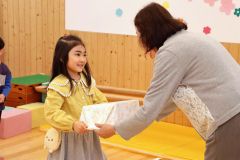 今城部長から絵本のセットを受け取る園児
