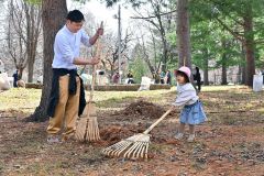 枝や枯れ葉などをかき集める親子（１４日、金野和彦撮影）