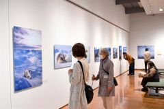 アラスカに暮らす野生動物の姿を捉えた星野氏の作品に見入る来場者（２０日、午前１０時半ごろ。金野和彦撮影）