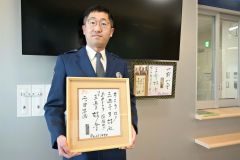 好楽さんから二つ目昇進を告げられた岡崎巡査長。手には昇進を告げる色紙を持っている。奥は好楽さんが帯広署宛てに書いた色紙とメッセージ