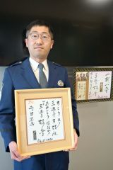 好楽さんから二つ目昇進を告げられた岡崎巡査長。手には昇進を告げる色紙を持っている。奥は好楽さんが帯広署宛てに書いた色紙とメッセージ