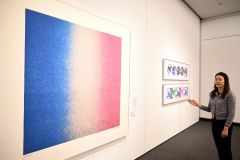 百瀬寿の「Ｓｑｕａｒｅ－Ｖｅｒｔｉｃａｌ　Ｂｌｕｅ　ｔｏ　Ｍａｇｅｎｔａ」の前で来場を呼び掛ける学芸員の敷田さん