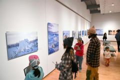 アラスカに暮らす野生動物の姿を捉えた星野氏の作品に見入る来場者（２０日、午前１０時４５分ごろ。金野和彦撮影）