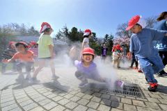 ミスト噴水で遊ぶ園児たち（２６日、午前１０時１５分ごろ、音更町役場前で。金野和彦撮影）