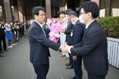 庁舎玄関前で、見送りの役場職員と握手する村瀬優町長