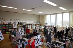 書いた平仮名の「あ」を掲げる児童ら
