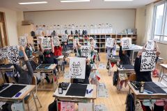 筆使いの練習で完成した鬼の顔を掲げる児童ら
