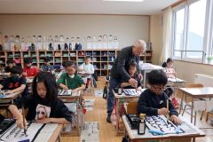 筆使いの練習を繰り返す児童ら（２列目右が野坂さん）