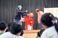 燃え上がる炎を消そうとする団員と心配そうに見つめる園児ら（２４日１０時５５４分ごろ、帯西幼稚園）