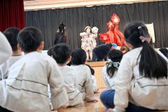 炎と煙がのぼる中、低い姿勢で逃げる登場人物とそれを見る園児ら（２４日１１時００分ごろ、帯西幼稚園）