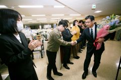 初登庁し、出迎えの職員と握手を交わす田中新町長（３０日午前８時４０分、石原秀樹通信員撮影）
