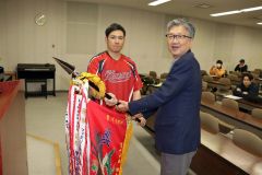 優勝旗を返還する川端さん(左)と鈴木支部長