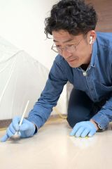 真剣な面持ちでフローリングを補修する田中さん