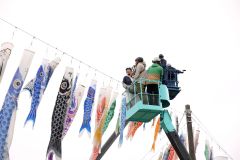 高所作業車に乗ってこいのぼりを上から眺める家族連れ