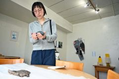 土屋さんの作品を構成する気仙沼の石を触り、持つ来場者