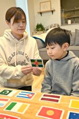 母かおるさん（左）と国旗カードで遊びながら学ぶ康さん（右）