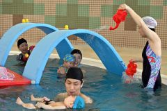 楽しくトンネルをくぐり、水を浴びる親子連れ