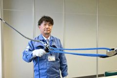 開発した工具と城之内さん。青いロープを引くと、電線同士を近づけられる