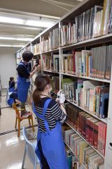 たくさんある本を一冊ずつ丁寧に確認する職員