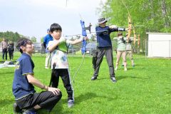 的をめがけて弓を引く体験会参加者ら