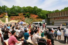 ツツジが赤く色づく会場内で、アトラクションを楽しむ来場者（１９日午前１１時半、石原秀樹通信員撮影）