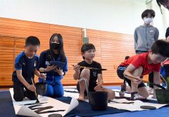 高校生に指導を受けながら筆を運ぶ児童ら