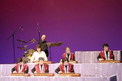 そろいの赤い衣装で演奏を聴かせる出演者