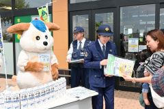 チラシを配る署員と受け取る親子（２３日午前１０時２５分ごろ、ダイイチ白樺店前）