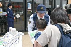 親子にチラシを配る帯広署員（２３日午前１０時２５分ごろ、ダイイチ白樺店前）