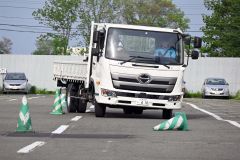 駐車場でパイロンスラロームを行うトラックドライバーら
