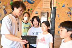 子どもたちが登る様子を撮った映像を見せながら指導する前田さん（左）