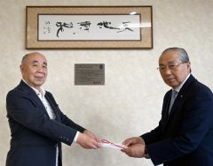 掲示された中村海墨氏の遺作の書「天地清和」の前で、村岡さん（左）から目録を受ける小野町長