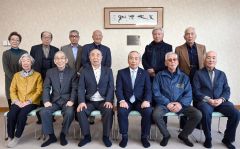 掲げられた中村海墨氏の遺作の書「天地清和」の前で記念撮影する村岡さん（中央左）と小・中学校の同級生ら。中央右は小野町長