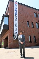 役場庁舎に掲げられた懸垂幕を前にする阿部町長（７日午前１１時５５分ごろ）