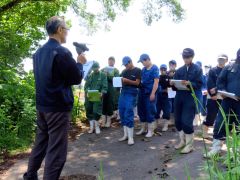 塩沢さんから草地の様子について説明を受ける生徒たち