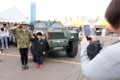 自衛隊車両の前で制服を着て記念撮影する子ども（助川かおる通信員撮影）