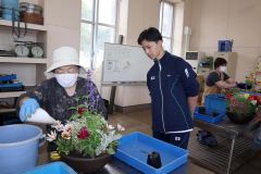生徒（左から２人目）にアドバイスをもらって寄せ植えに挑戦する受講者（左）