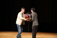 藤監督から花束を渡される逢坂監督（右）