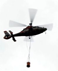 バケットをつるして上空３００メートルまで上昇するヘリコプター（須貝拓也撮影）