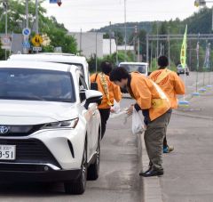 ドライバーに啓発資料を手渡し交通安全を呼びかける参加者たち