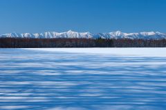 広尾町の豊似で撮影した雪原に防風林の影が伸び、遠くにそびえる日高山脈をとらえた作品（２０１０年、戸張さん撮影）