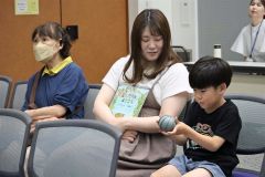 伊藤さんが持参したダンゴムシの模型に触れる親子連れ