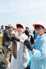 網に掛かった魚を手にする児童
