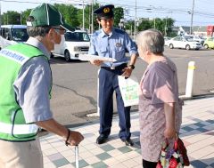 買い物客に啓発グッズを配布し交通安全を呼び掛ける署員ら
