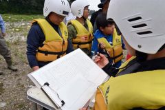 川で見つけた生き物をチェックして水質を調べる児童
