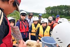 川で見つけた生き物から水質を調べる児童