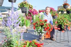 花に囲まれ、笑顔を見せる木幡重雄さん
