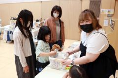 お菓子のつかみ取りに挑戦する子どもたち。右は岡崎さん