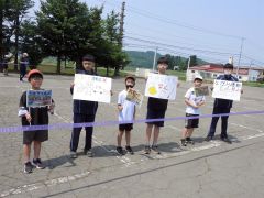 手書きのボードと小旗を手にする小中学生